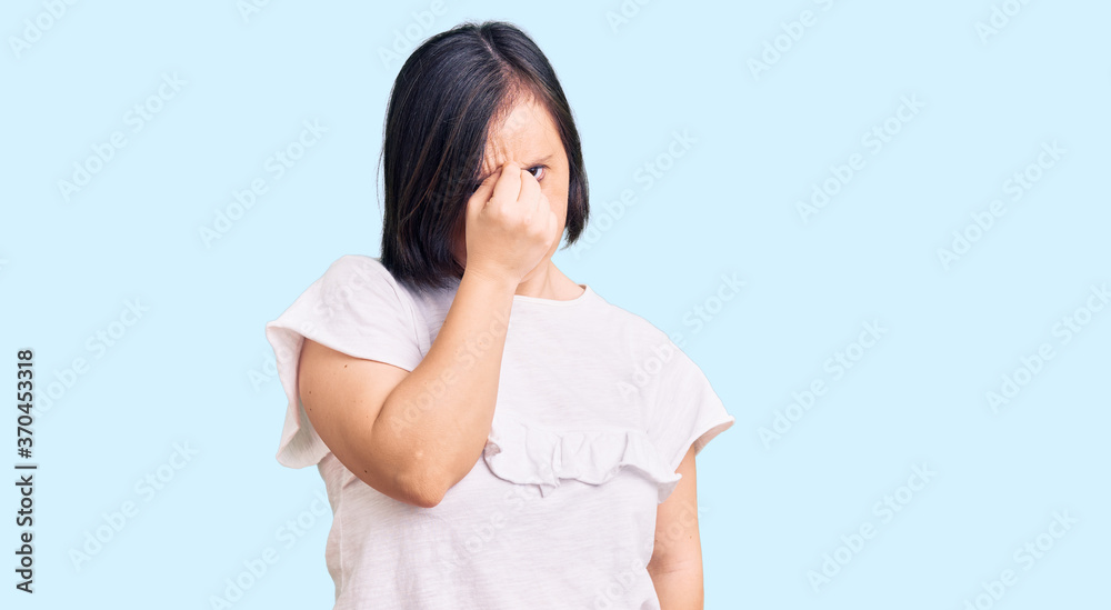 Brunette woman with down syndrome wearing casual white tshirt tired rubbing nose and eyes feeling fatigue and headache. stress and frustration concept. Brunette woman with down syndrome wearing casual white tshirt tired rubbing nose and eyes feeling fatigue and headache. stress and frustration concept.
