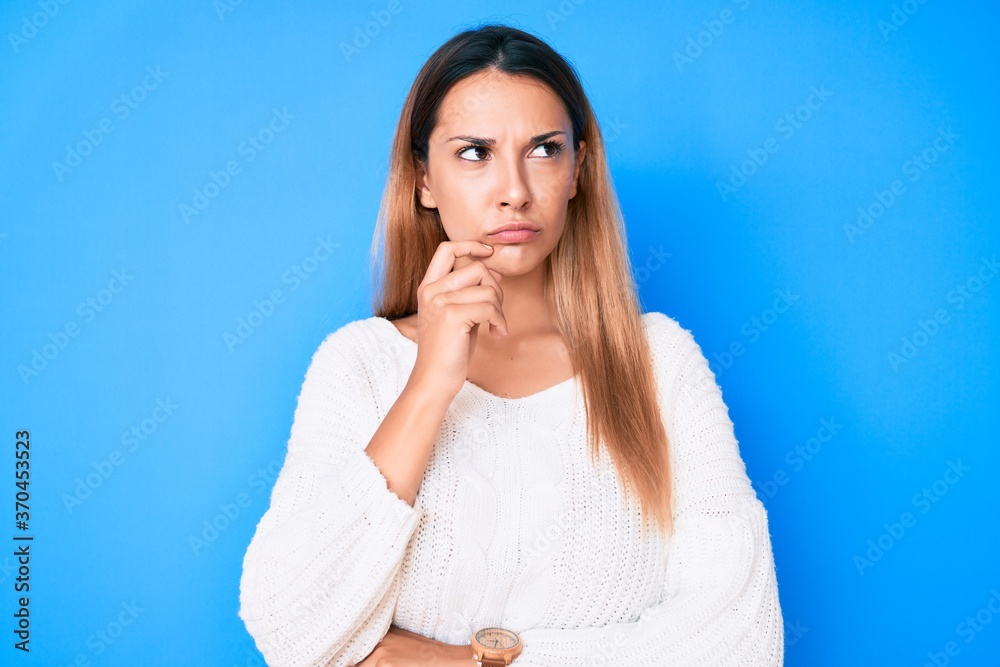 Young brunette woman wearing casual sweater serious face thinking about question with hand on chin, thoughtful about confusing idea Young brunette woman wearing casual sweater serious face thinking about question with hand on chin, thoughtful about confusing idea
