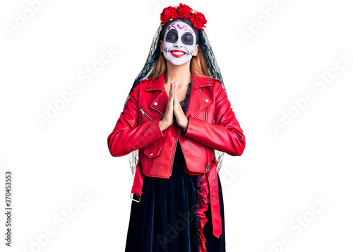 Woman wearing day of the dead costume over background praying with hands together asking for forgiveness smiling confident.