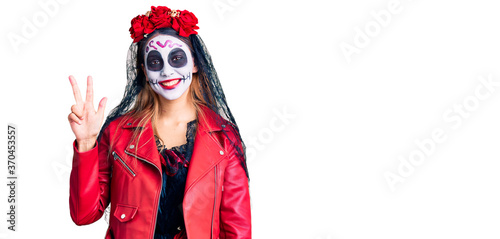 Woman wearing day of the dead costume over background showing and pointing up with fingers number three while smiling confident and happy.