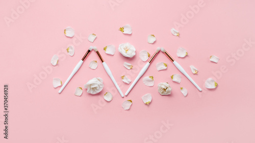 Makeup brushes and flowerss on white background. Horizontal view copyspace.