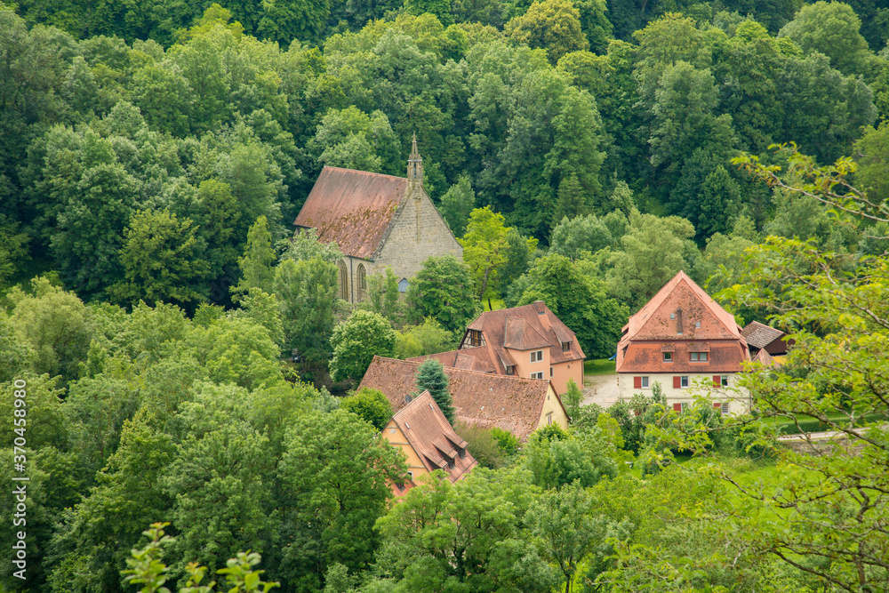 Traditional homes and a church in a forested area on the outskirts of Rothenburg ob der Tauber, Germany Traditional homes and a church in a forested area on the outskirts of Rothenburg ob der Tauber, Germany