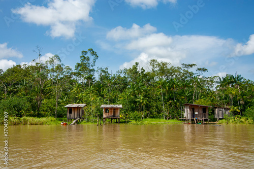 Casas ribeirinhas de madeira em margem de rio na floresta amazônica, Brasil.