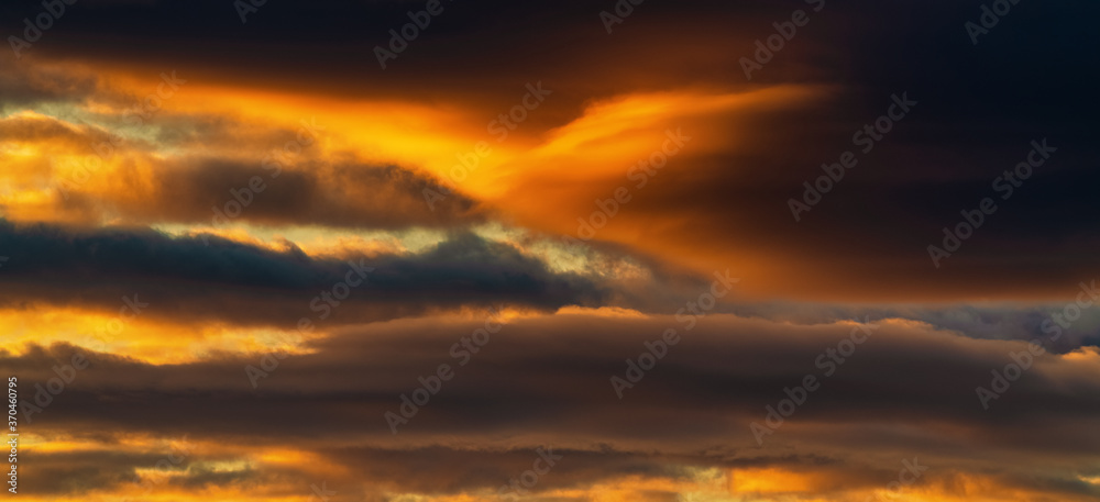 Panorama view of dramatic clouds illuminated rising of sun floating in sky to change weather. Soft focus, defocus, motion blur landscape. Impressive multicolored cloudscape and meteorology background.