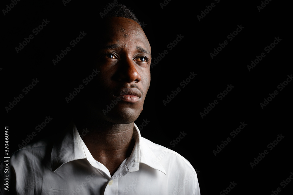 Young African businessman in the dark against black background Young African businessman in the dark against black background