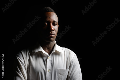 Young African businessman in the dark against black background