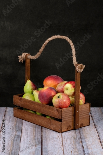 Ripe apples  pears and peaches in a wooden box