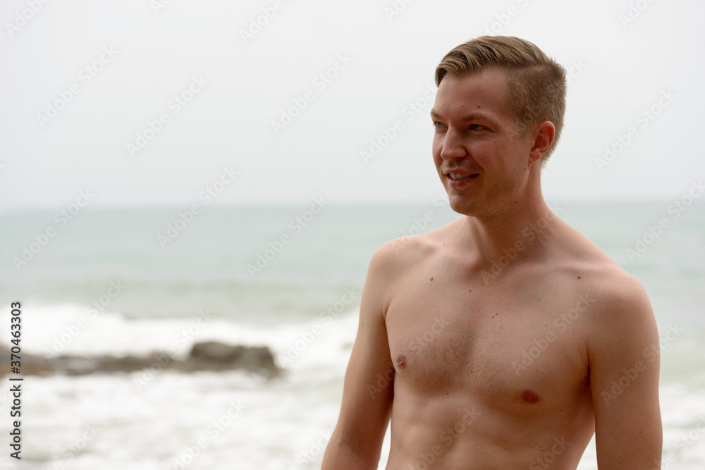 Young handsome shirtless tourist man relaxing at the beach Young handsome shirtless tourist man relaxing at the beach
