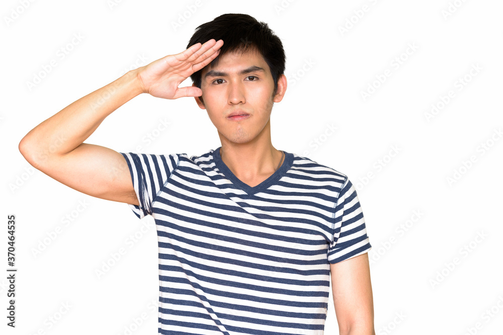 Studio shot of young handsome Asian man saluting isolated against white background Studio shot of young handsome Asian man saluting isolated against white background