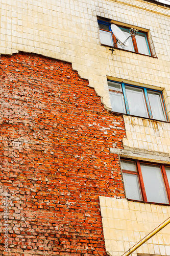 Old high-rise building with broken windows, crumbling walls covered with cracks and scratches photo