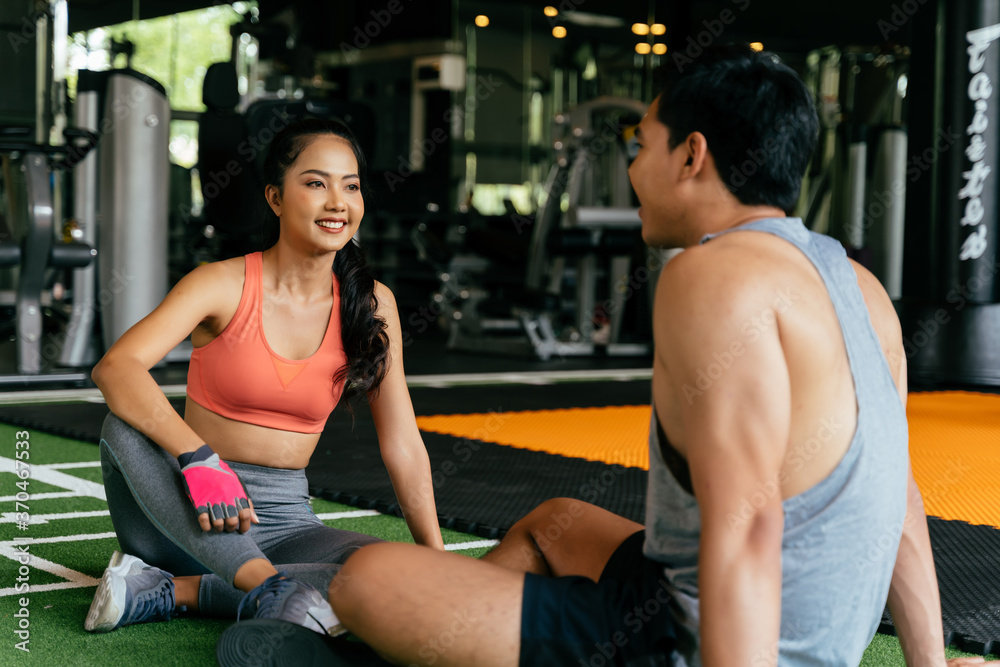 Face of Young Asian mixed sporty woman chatting with a muscuar man sitting on the floor at fitness gym. Healthy couple concept Face of Young Asian mixed sporty woman chatting with a muscuar man sitting on the floor at fitness gym. Healthy couple concept