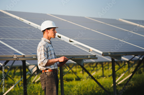 Installing and wiring of stand-alone solar photo voltaic panel system. Close-up of young electrician in hard-hat. Alternative energy concept.