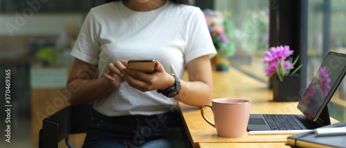 Female hands using smartphone while sitting at portable workspace in cafe
