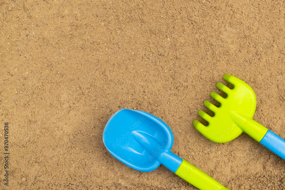 Shovel and rake in sandbox. Outdoor children's sand toys. Summer concept. With place for text. Shovel and rake in sandbox. Outdoor children's sand toys. Summer concept. With place for text.