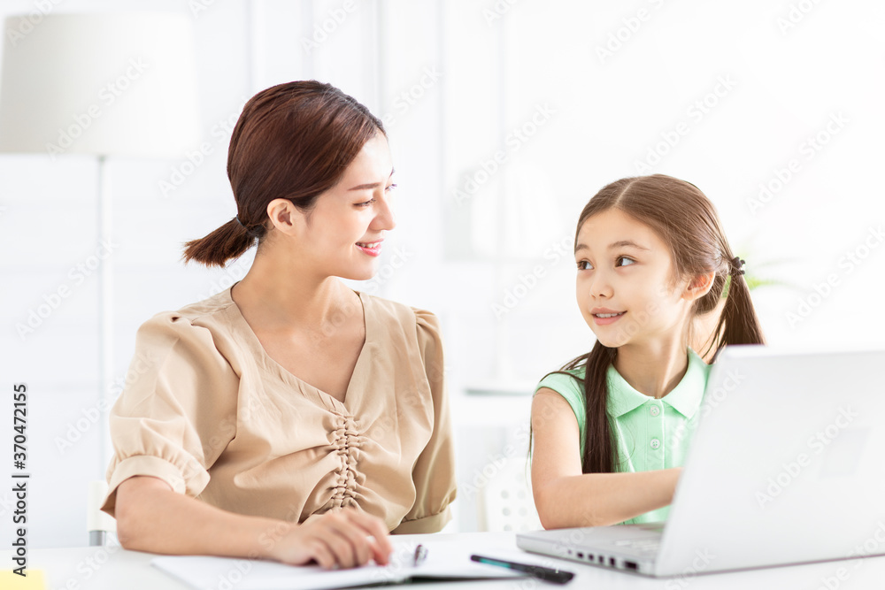 Mother is working and teaching her daughter doing home work Mother is working and teaching her daughter doing home work