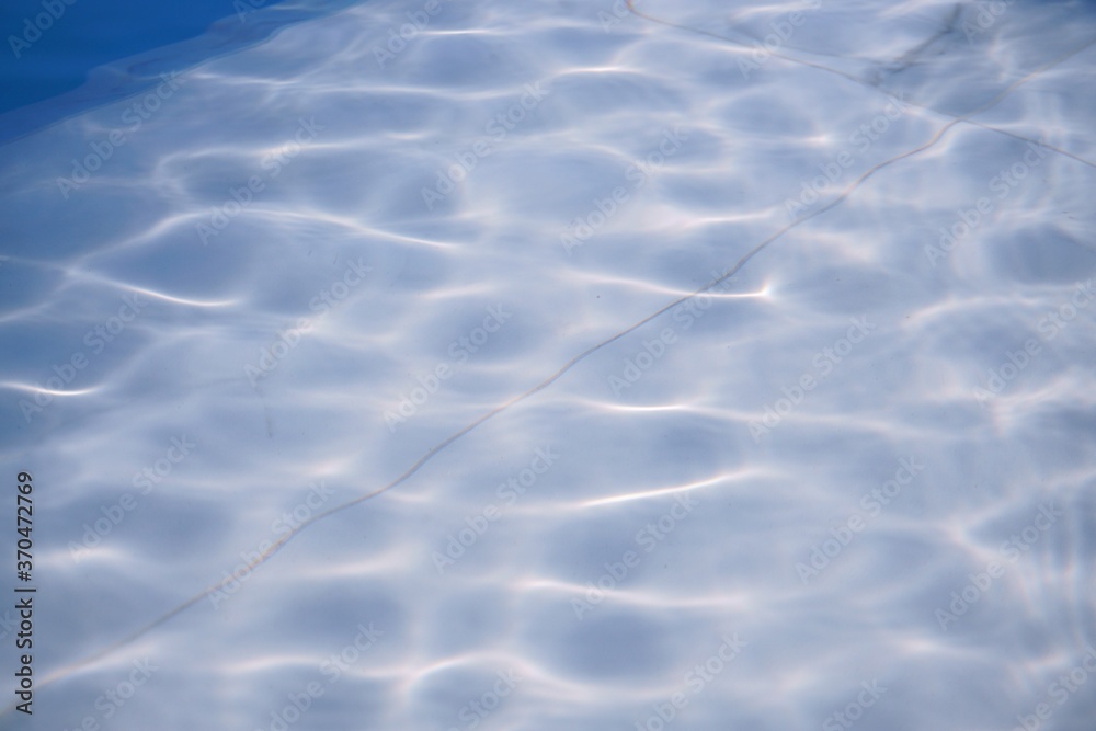 Reflection of water surface above white tiles pattern in swimming pool Reflection of water surface above white tiles pattern in swimming pool