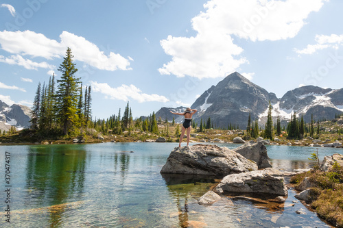 Gwillim Lakes, beautiful mountains and pristine alpine lakes in Valhalla provincial park, BC, Canada, West Kootenays region. Blue water, a woman standing in the swimsuit enjoying the view