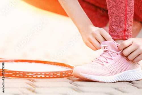 Sporty young woman tying shoelaces outdoors  closeup