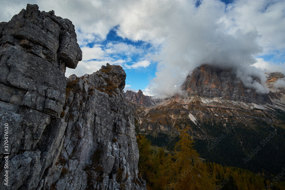 Rugged and rocky alpine mountain ranges with cloudy blue sky above in The Dolomites. These iconic mountain peaks are located at Cinque Torri in the Tyrol region of Italy.