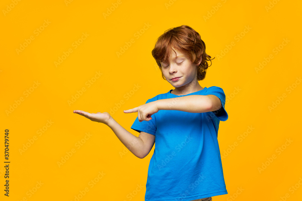 redheaded boy blue t-shirt yellow background freckles and point your finger to the side of your closed eyes redheaded boy blue t-shirt yellow background freckles and point your finger to the side of your closed eyes