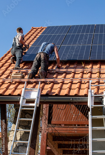  Workers installing solar electric panels on a house roof in  Ochojno. Poland