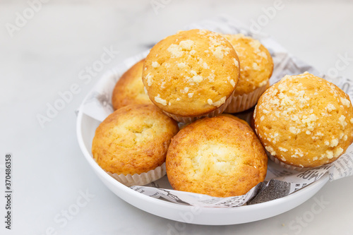 Freshly baked tasty vanilla muffins and muffins with crumble topping. Light grey background.