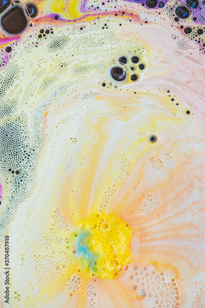 Bath foam with yellow and purple rainbow colors with bubbles in the water. Galaxy imagination. Marble texture background effect. Flat lay, top view, directly above