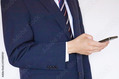 スマホを触っているスーツの男性