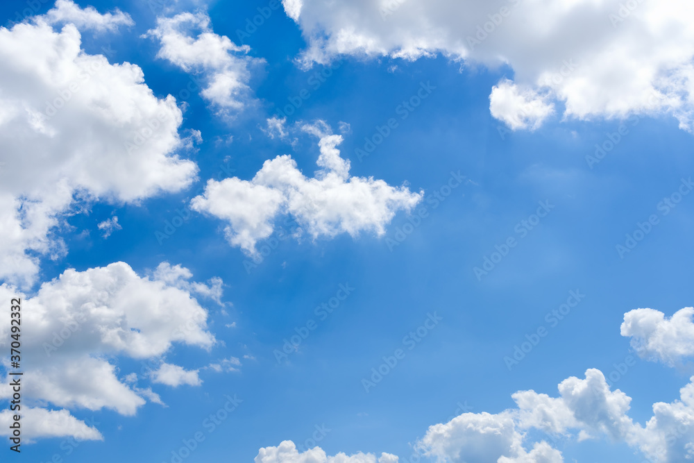 Bright blue sky and white fluffy clouds high in the bright blue summer sky on a day. Good sunny weather, seaside vacations and summer holidays. Scenic skyscape.