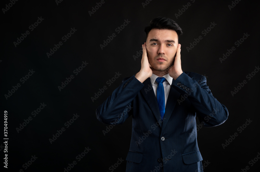 Portrait of business man wearing blue business suit and tie covering ears like deaf gesture Portrait of business man wearing blue business suit and tie covering ears like deaf gesture