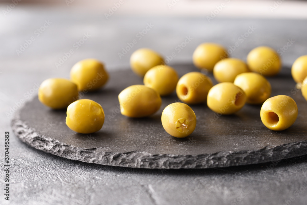 Green olives on the slate plate, on the gray background. Green olives on the slate plate, on the gray background.