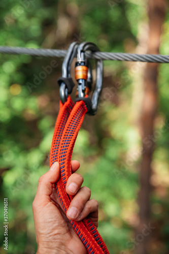 Rope park. The hand hooks the carabiners to the belay line. Close-up