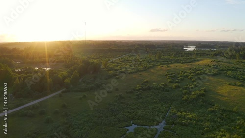 Flying over beautiful countryside landscape with field and trees, Latvian nature, summer sun.