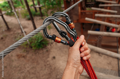 Rope park. The hand hooks the carabiners to the belay line. Close-up