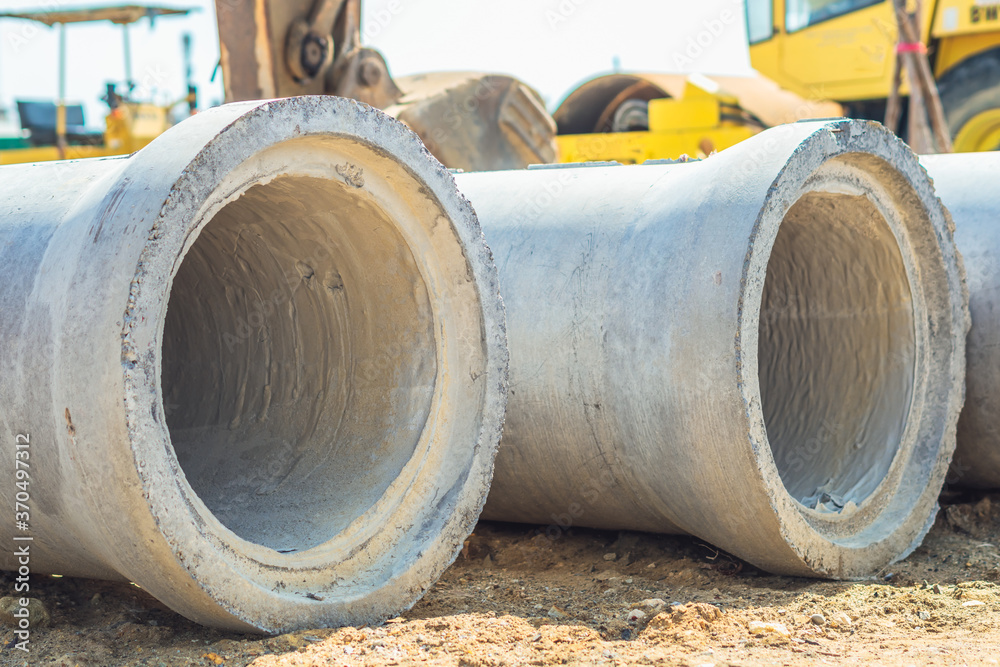 Stack of concrete drainage pipes for wells water discharges laying an external sewage system at a construction site outdoors warehouse. Civil infrastructure, industry manufacturing of cement products Stack of concrete drainage pipes for wells water discharges laying an external sewage system at a construction site outdoors warehouse. Civil infrastructure, industry manufacturing of cement products