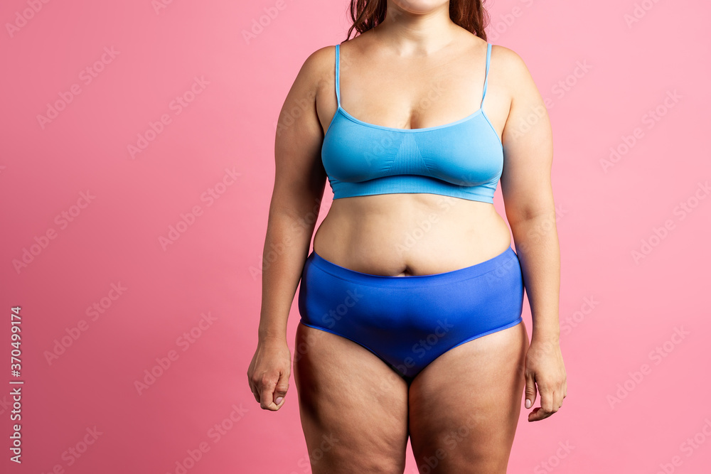 Plus size model in blue lingerie, fat woman on pink background