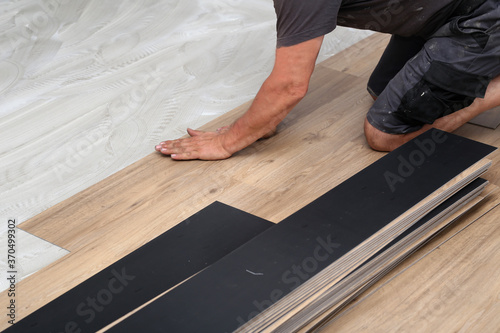 The worker installing new vinyl tile floor