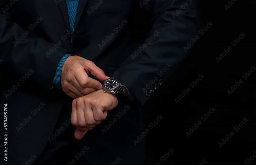 A wristwatch on the hand of a business man in a dark blue jacket.