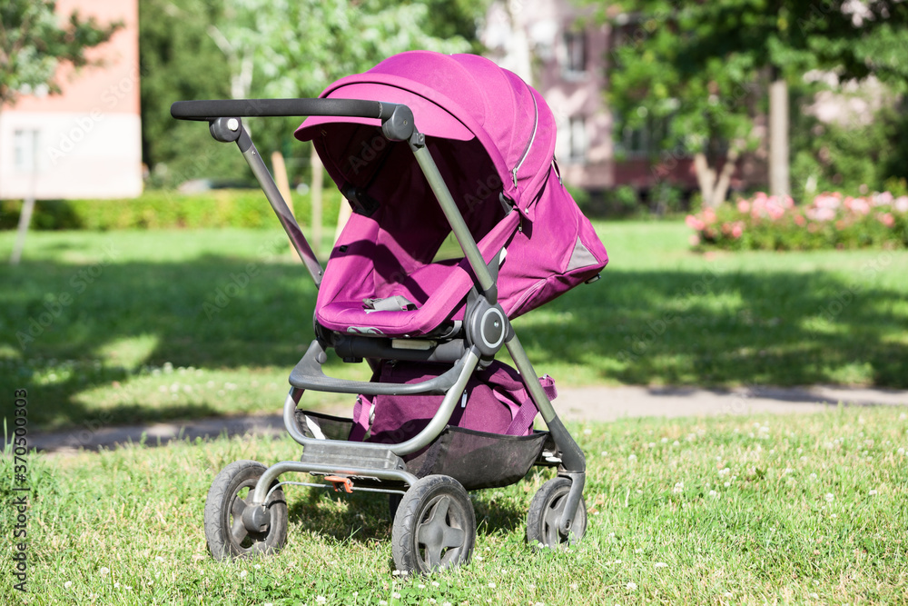 Baby pushchair is folded in lying position on green meadow in summer sunny park, an infant perambulator series Baby pushchair is folded in lying position on green meadow in summer sunny park, an infant perambulator series