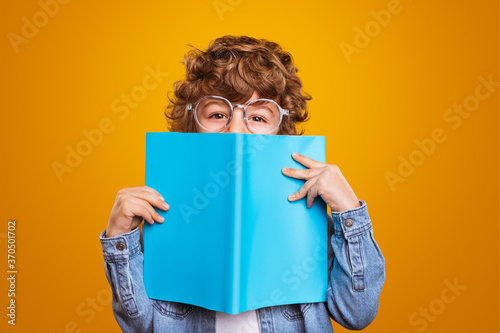 Happy schoolboy in glasses holding book