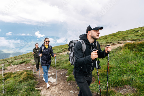 Group of hikers with backpacks on a mountain footpath. Tourists with nordic walking poles