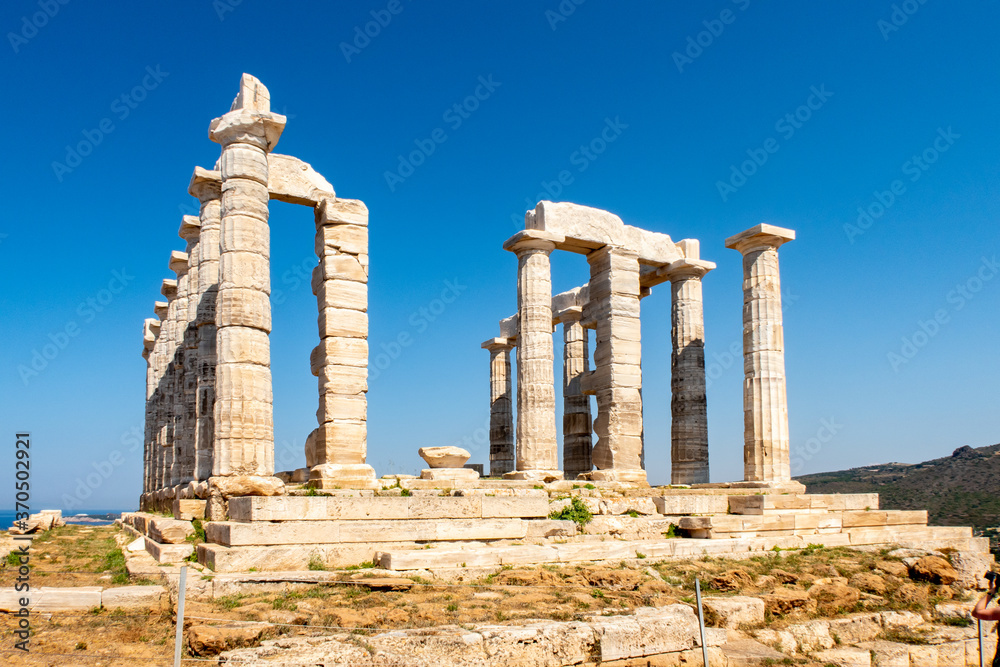 The ancient Greek Temple of Poseidon at Cape Sounion, doric columns and ruins on the hill with crystal blue sky background.