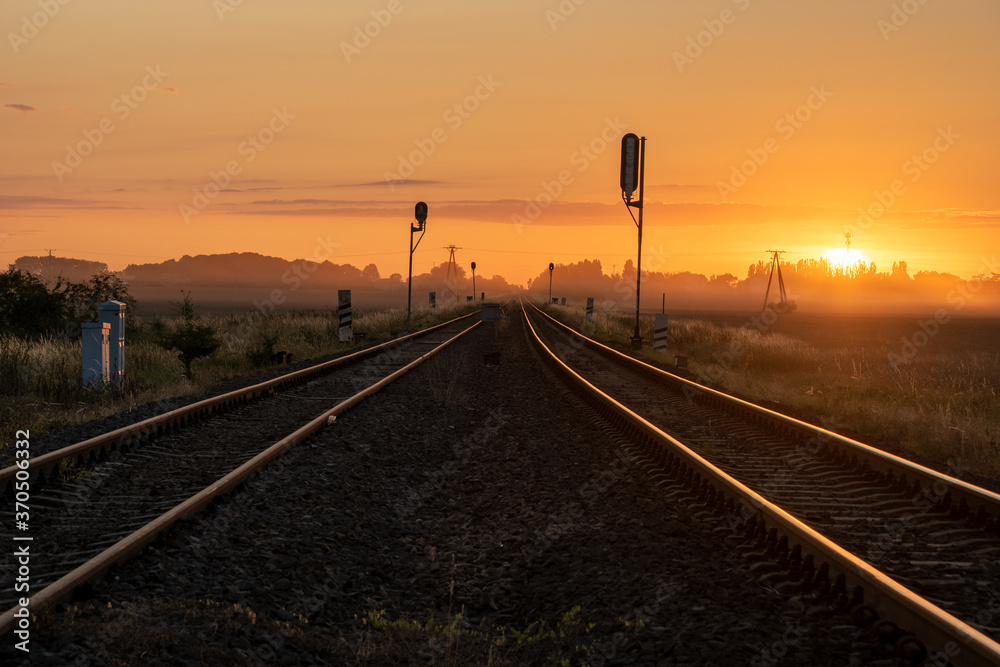 railroad tracks in the countryside during a beautiful misty sunrise