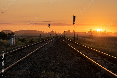 railroad tracks in the countryside during a beautiful misty sunrise