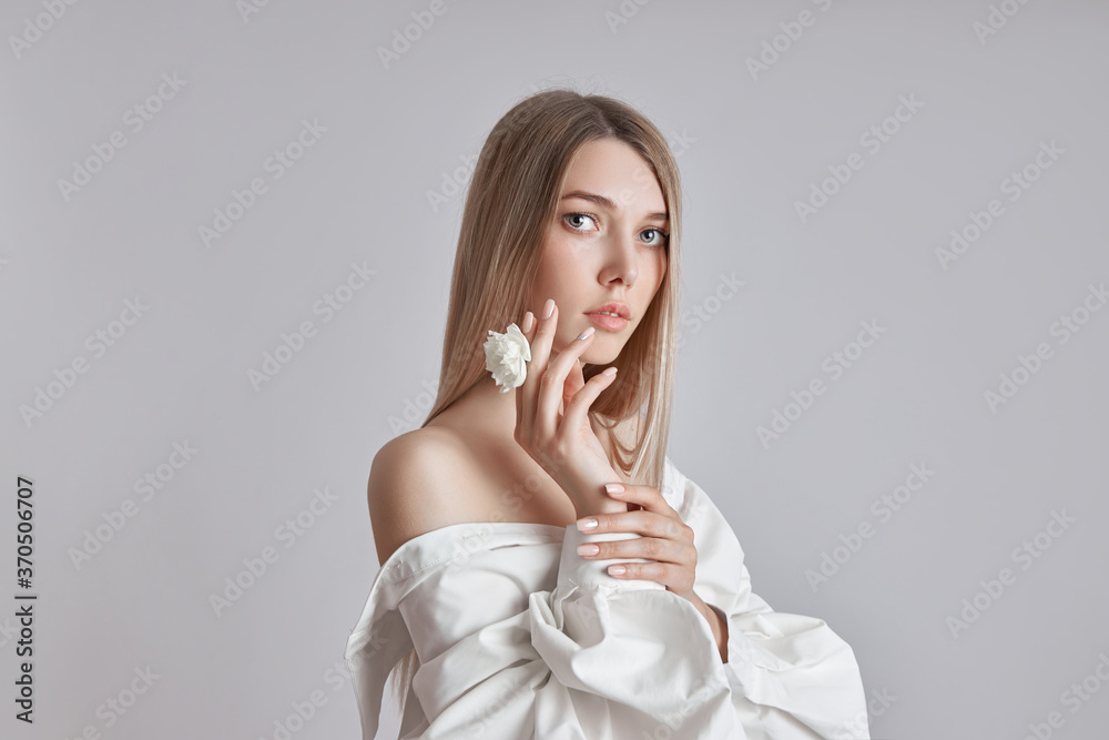 Blonde beauty woman holds white flower in hand. Beautiful soft hands and soft skin. Cosmetics for beauty hand care Blonde beauty woman holds white flower in hand. Beautiful soft hands and soft skin. Cosmetics for beauty hand care