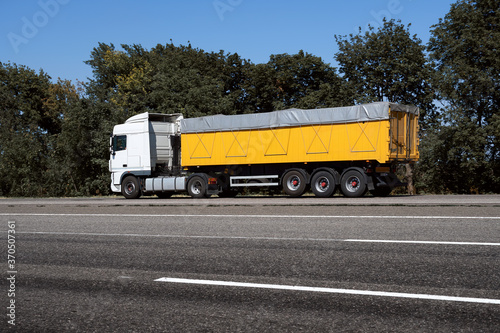 truck on the road, side view, empty space on a yellow container - concept of cargo transportation, trucking industry