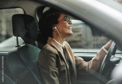Foto Businesswoman enjoying music while driving to work