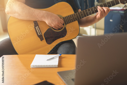 Man learns to play the guitar using online video lessons.