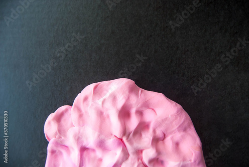 abstract background wavy shapes of pink color on a dark background from modeling dough.