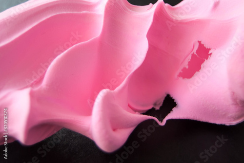 abstract background wavy shapes of pink color on a dark background from modeling dough.